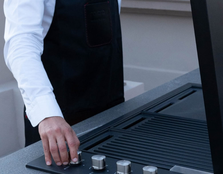CHEF QUI UTILISE LE GRILL SUR UNE CUISINE D’EXTÉRIEUR